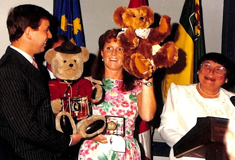 Prince Andrew, Sarah Ferguson, and Sylvia Fedoruk. Sarah is holding up a teddy bear made for her. 